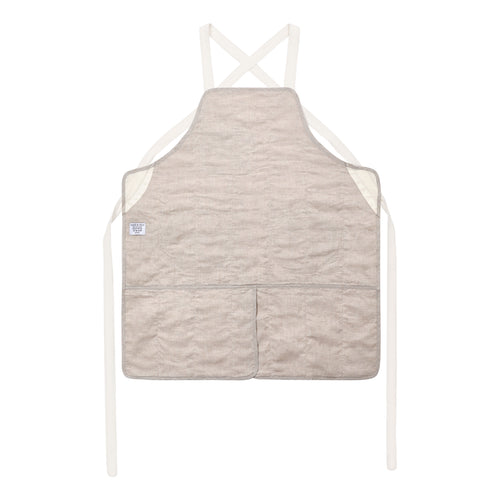 A light beige quilted chef apron with cream-colored straps and a small white brand tag on the left side, displayed against a solid white background.